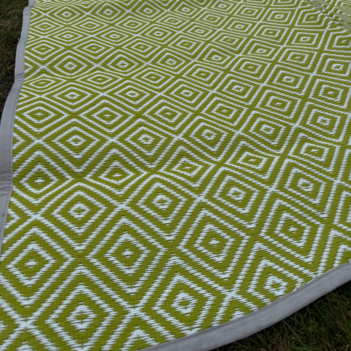Green diamond-pattern polypropylene mat with fabric edge rolled for detail view