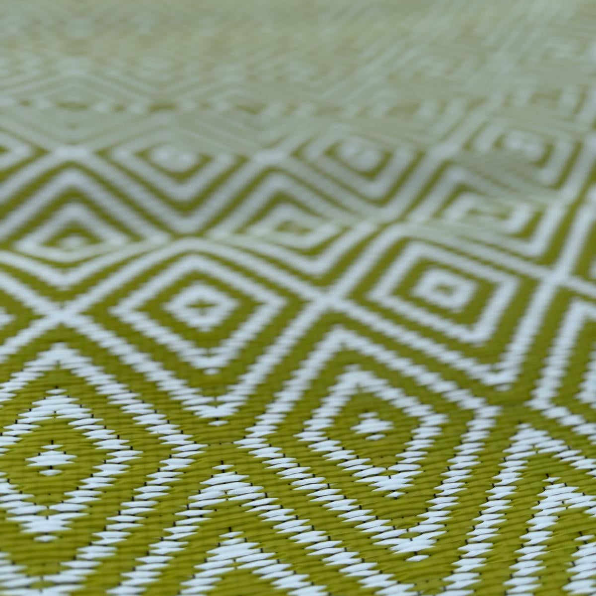 Full close-up of green diamond-pattern polypropylene flooring showing repeating geometric design