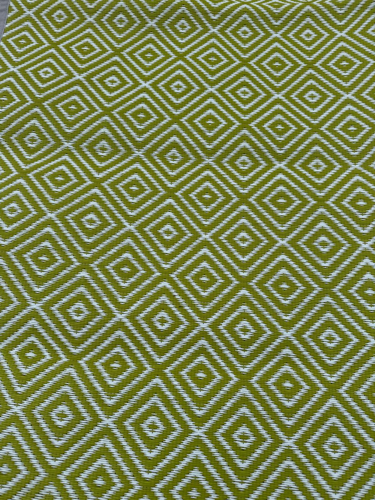 Green diamond-pattern polypropylene flooring with white geometric design shown in close-up outdoor view