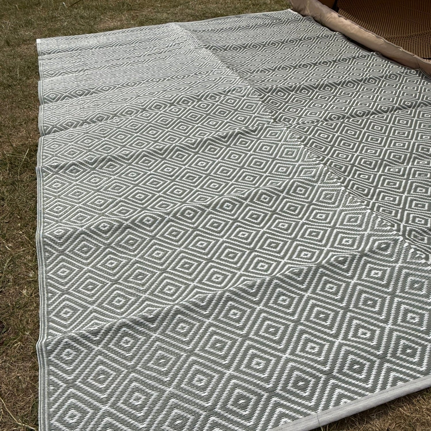 Gray and white geometric patterned rug on grass