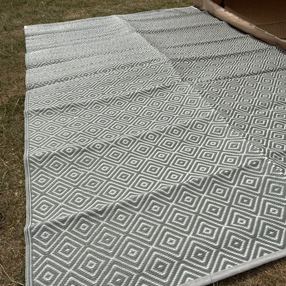 Gray and white geometric patterned rug on grass