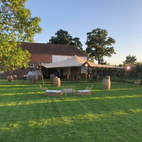 Stretch tent installed outdoors on a grassy field during sunset with poles and ropes