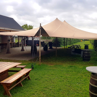 Stretch tent set up on a garden lawn with wooden poles and tension ropes