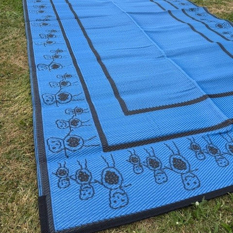 Blue rectangular camping mat for kids with decorative border art, laid out on grass