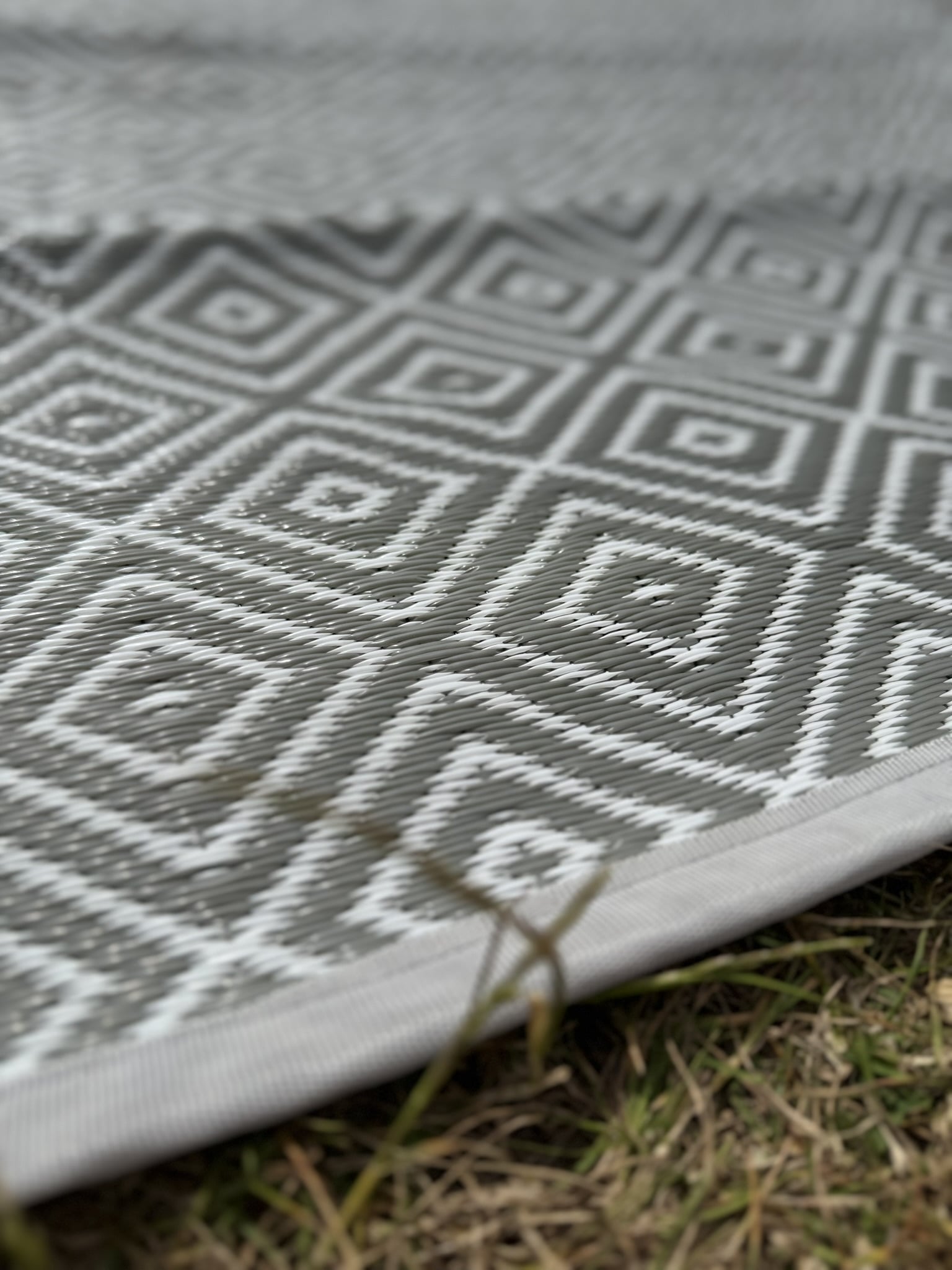 Gray and white geometric patterned mat on grass