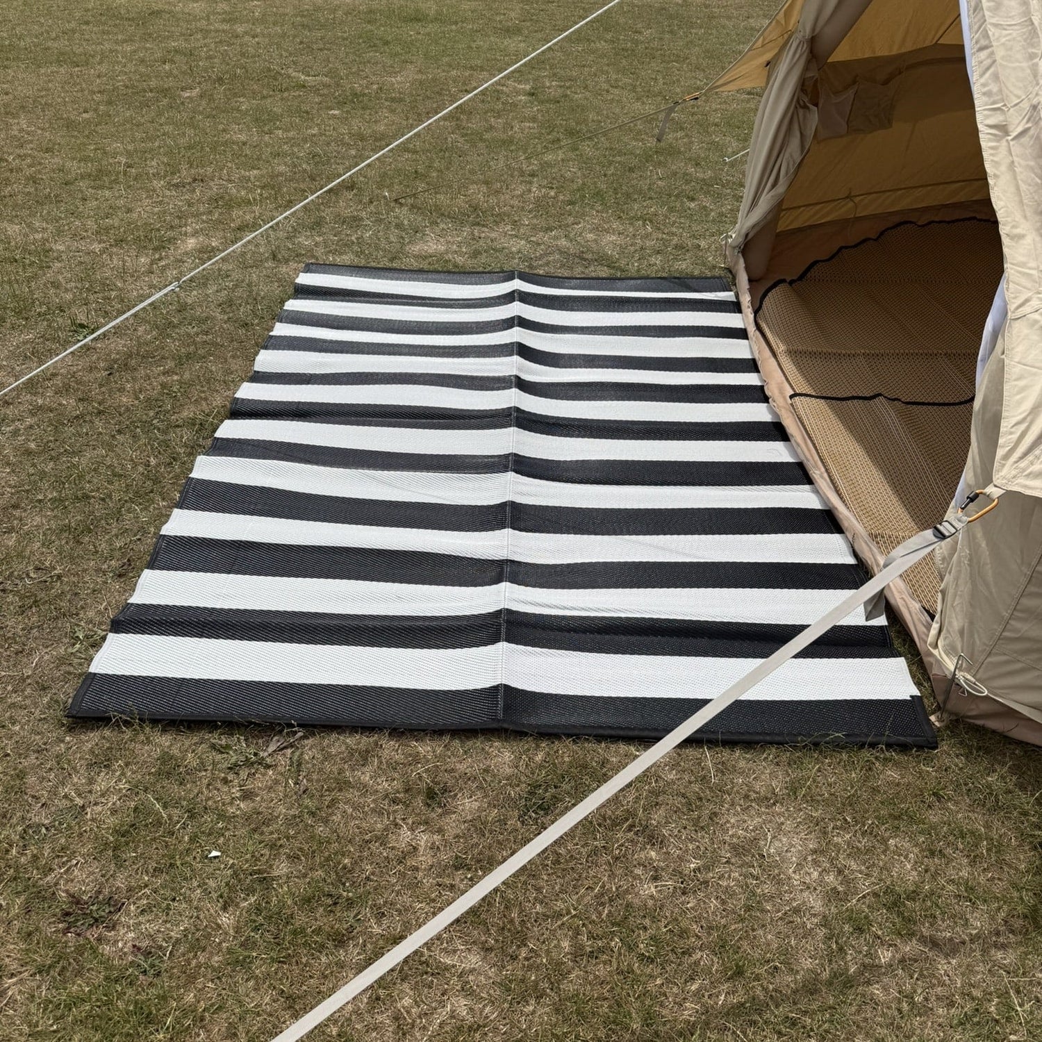 Black and white striped mat on grass next to a tent