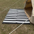 Black and white striped mat on grass next to a tent