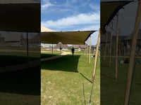 Thumbnail showing a green outdoor stretch tent setup supported by wooden poles